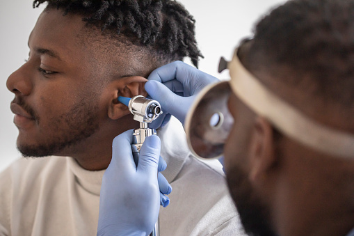male  doctor carefully holding the ear of his patient to establish a clearer view of the inside of his ear